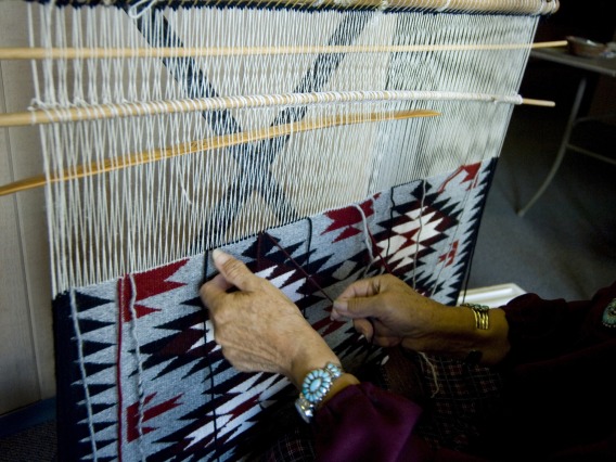 Native American weaving a traditional rug