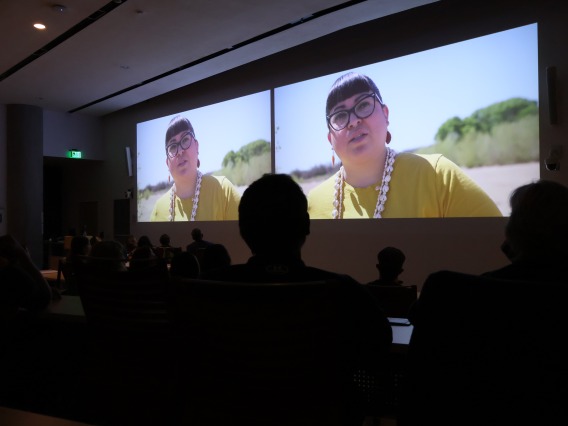 Audience members look on during the Making Arizona screening as Jacelle Ramon-Sauberan can be seen projected in two side-by-side images at the front of the room.